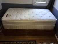 Full side view of the single wooden bed frame with two drawers visible beneath and mattress on top