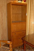 Full front view of walnut finish bar cabinet showing lower cupboard with double doors, above drawer, middle drop-down bar storage, and upper open shelves.