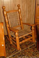 Front view of maple rocking chair with rawhide woven seat and backrest.