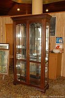 Front view of the tall Thomasville display cabinet showing mahogany finish, glass doors, and interior shelves.