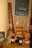 Wooden bar decor items, salt and pepper mills, cups, large carved spoon and fork, wooden barrel, and a small bar closed sign.