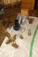 Overview of the lot with figurines, dishes, vase, box and frame on a white cloth.