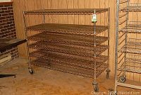 Front and side view of the rolling metal shelving unit showing five wire mesh shelves and caster wheels.
