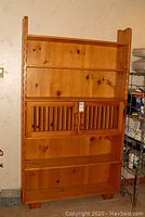 Full view of the vintage solid pine shelving unit showing upper open shelves, middle sliding slatted doors, and lower open shelves.