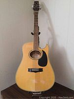 Full front view of guitar standing on table against paneled wall