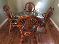 Full set of round glass top table with four chairs viewed from rear