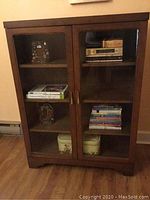 Front view of walnut bookcase showing two glass doors with interior shelves and items