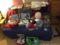 Wide view of the craft supplies laid out on a covered surface including yarn, fabric, paint bottles, decorative stones, and papers