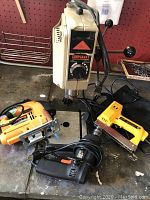 Overview of all tools including the Shopcraft drill press, Chicago orbital jigsaw, Black & Decker drill, and electric staple gun on a workbench.