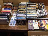 Full view of assorted DVDs and VHS tapes laid out on a table showing variety and quantity