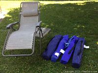 Gravity chair with four folded camping chairs on grass. Shows general lot contents.