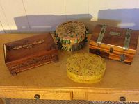 Four decorative trinket boxes arranged on table surface