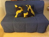Front view of futon in sofa position with navy blue cover and two throw pillows