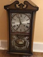 Front view of the wooden case, scroll-top pediment, silver dial marked Regal