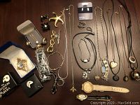 Flat lay of assorted costume jewelry including necklaces, pins, rings, and watches on wooden surface
