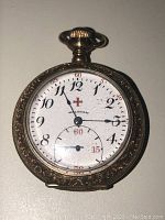 Front view of watch showing dial, hands, red cross emblem and subsidiary seconds register
