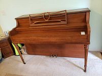 Front view of Mendelsohn upright piano showing decorative carved legs and music stand, wooden medium brown finish