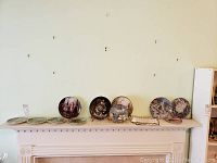 Full view of 11 collectible plates arranged on a mantel, showing variety in size and design, some with Certificates of Authenticity.