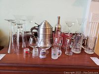 Full set of vintage barware glassware with cocktail shaker and ice bucket on wooden sideboard