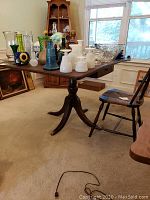 Full view of drop leaf table with decorative items on top and chair beside.