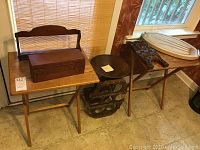Two wooden folding tables with various wooden kitchen items on top and beneath, including a recipe box, spice rack, wine rack, bowl, cutting board, and cookbook holder