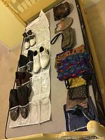 Overview of men’s shoes in various colors and styles on the left side, and a collection of women’s purses, scarves, and belts on the right side arranged on a flat surface.