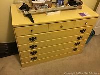 Front view of yellow painted 3 drawer dresser showing drawer pulls and surface condition.
