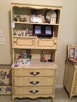 Full view of cream colored dresser and hutch showing three large drawers on dresser and two sliding doors on hutch, French Provincial style with smudges and dings.