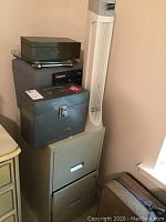 Overview image showing the fan, file cabinet, strong boxes and Sentry safe stacked on top of the cabinet.