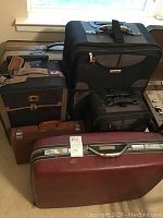 Photo showing all six luggage pieces, including 5 suitcases and 1 briefcase, from different angles mostly upright on the floor near a window.