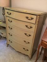 Front view of French Provincial style dresser showing five drawers and decorative drawer pulls.
