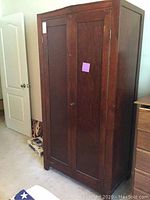 Full front view of the dark wooden armoire showing two paneled doors.