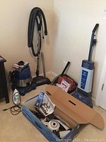 Photo showing Ocean Blue shop vacuum with attached hose, Eureka canister vacuum, Koblenz floor cleaner, and Black & Decker iron on floor.