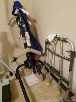 Portable patient lift and walker positioned upright, showing sling, handles, and wheels