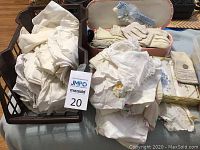 Large collection of white and off-white linen handkerchiefs stacked in a crate and folded, some appear new others worn.