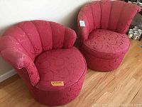 Pair of red damask fabric accent chairs with scalloped backs and round pedestal bases taken from front angle.