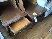 Two brown vintage wooden side tables placed side by side showing front view with drawer open on one table