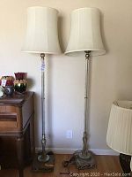 Photo of the pair of vintage floor lamps standing side by side showing clear glass rods and cream fabric shades