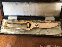 Close-up of ornate gold-toned scissors with decorative handles in lined presentation box