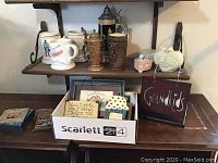 Wide view of wooden shelves with steins, box with framed prints, and heart-shaped ornament.