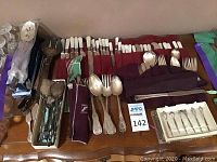 Overview of assortment of silverplate and sterling flatware and utensils laid on table