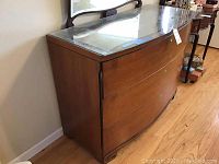 Front angle view showing wood dresser with three curved drawers and glass top surface.