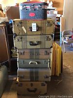 Stack of seven suitcases showing all from side angle including fabric textures and colors
