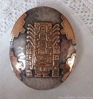Front view of large vintage oval pendant brooch with hammered silver and applied 18K gold Inca design.