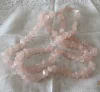 Full view of the vintage rose quartz chip necklace laid out on white cloth, showing length and chip details.