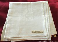 Folded white linen serviette showing subtle woven pattern and original 'All Linen Made in Ireland' label in corner.