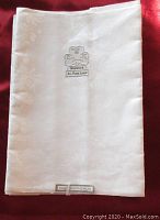 Single folded white linen serviette showing chrysanthemum pattern and Shamrock label.