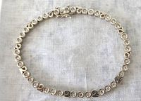 Full view of the silver CZ tennis bracelet against white textured fabric background