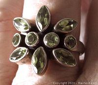 Close-up top view of sterling silver ring featuring multiple peridot-colored stones clustered in a floral/abstract pattern.