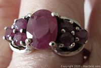 Close-up top view of the sterling silver ring with central oval ruby and six smaller rubies side-clawed set.